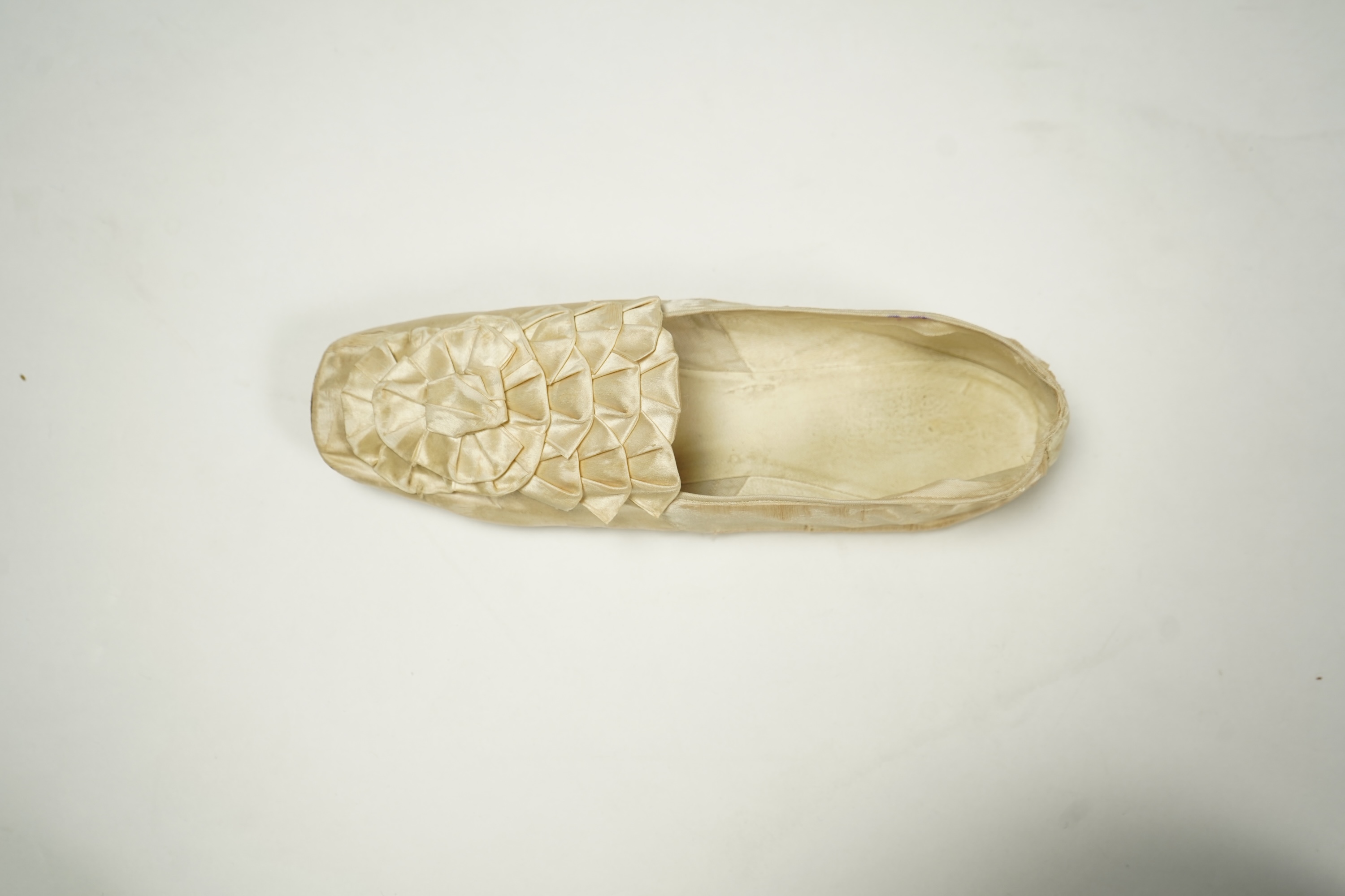 A 19th century hand made cream kid leather ladies ankle boot and four differing cream silk and satin single wedding shoes. All with leather soles. Possibly a traveller's sample range. Boots 24.5cm long (heel to toe). Con